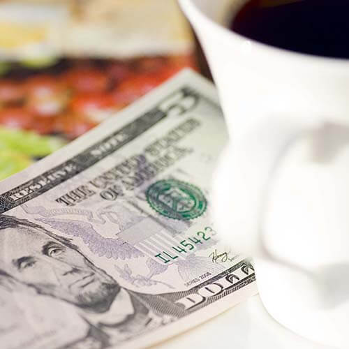 five dollar bill under coffee cup