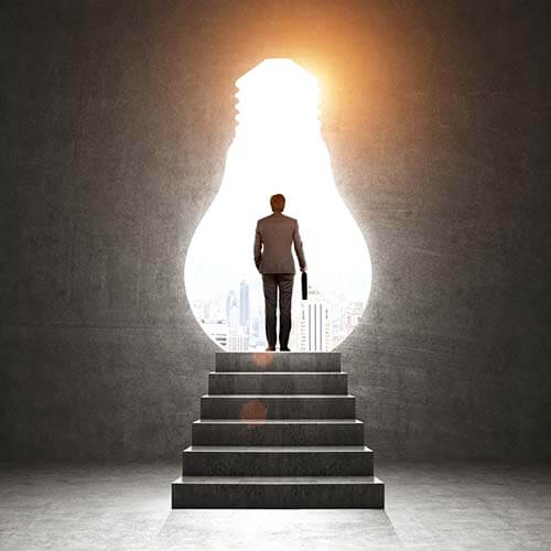 Man on top of stairs looking into lightbulb shaped opening