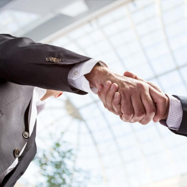Two men shaking hands in business building.