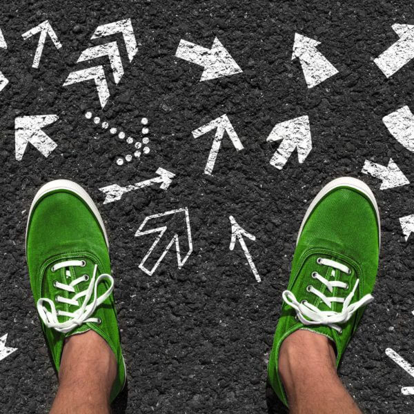 green tennis shoes on black pavement with arrows