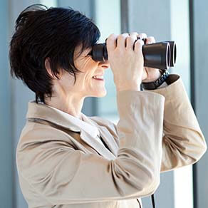 woman looking through binoculars in office
