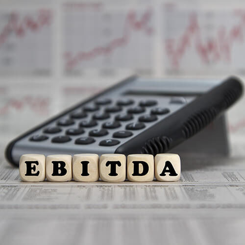 EBITDA word built with letter cubes on newspaper background