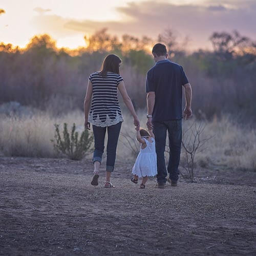 Couple with young child walking down road