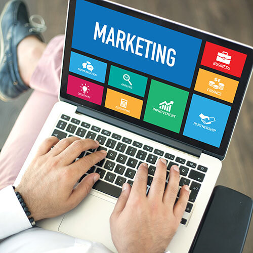 People using laptop in an office and MARKETING concept on screen