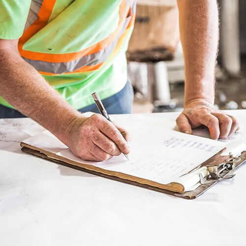 Construction worker looking at clipboard holding a pencil