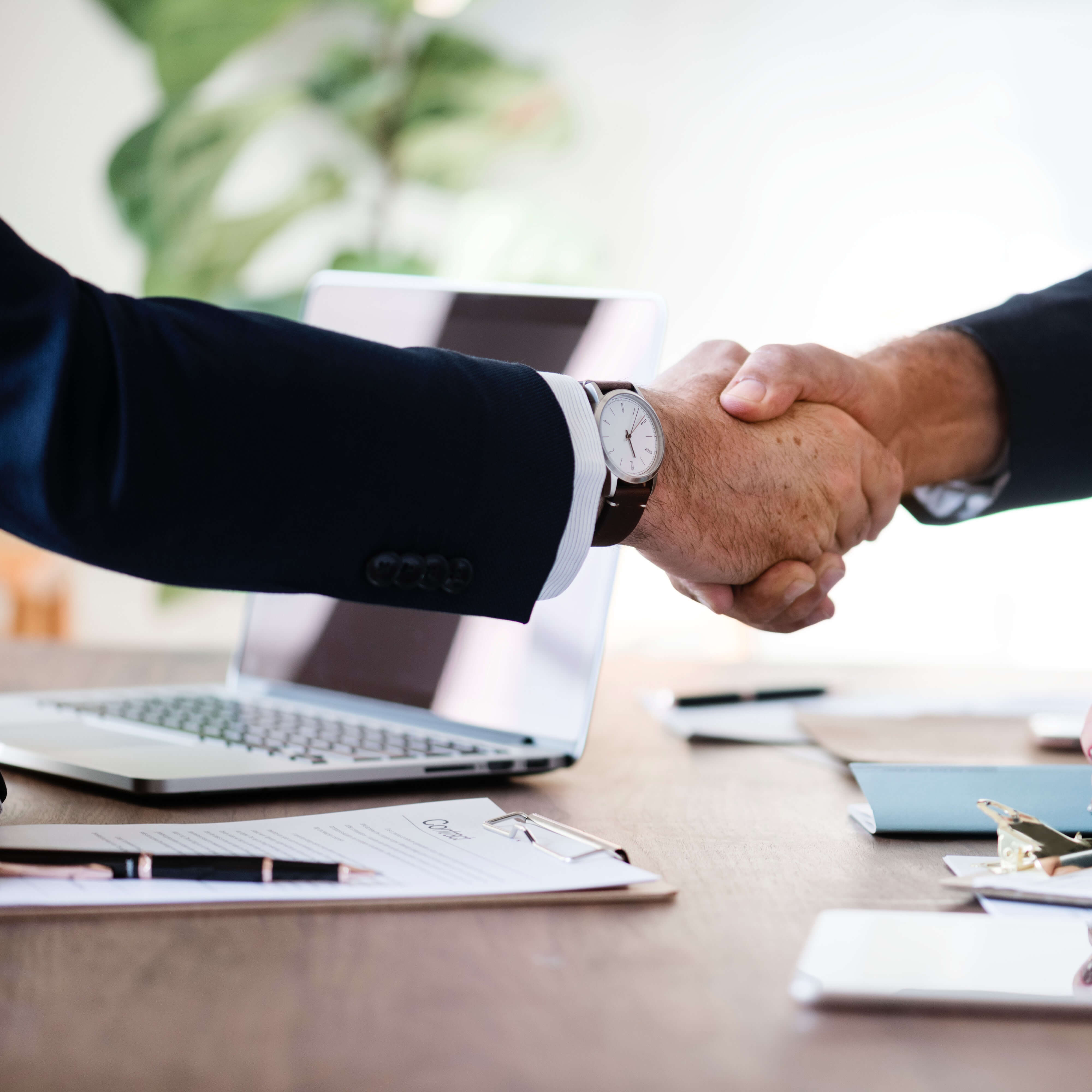 Two men shaking hands over a table with paper