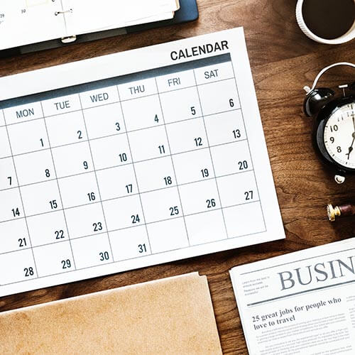 calendar on desk with newspaper and clock