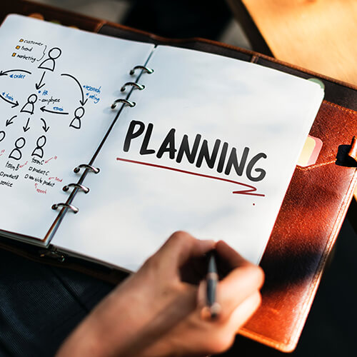 hand with pen writing in planner